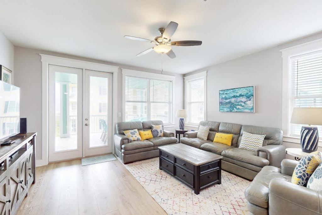 a living room with a couch and a ceiling fan at Sand Swept in Galveston