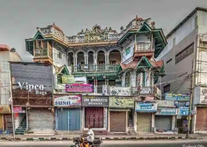 a man riding a motorcycle in front of a building at Umbrella Comfy Stays-Subbu in Madurai