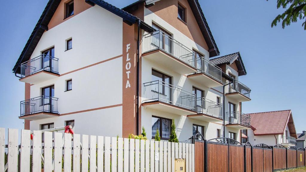an apartment building with a fence in front of it at Flota in Ostrowo