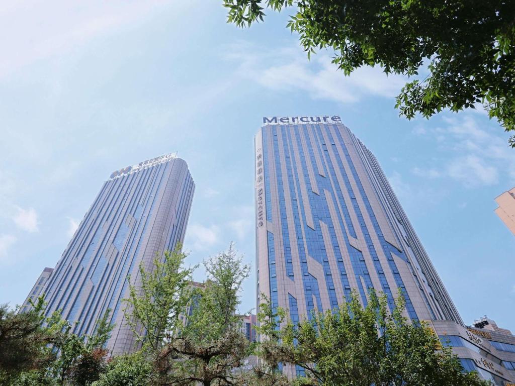two tall skyscrapers in a city with trees at Mercure Anyang Downtown in Anyang
