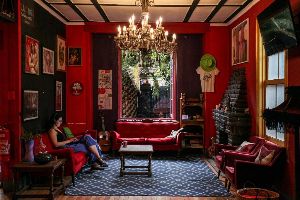 two people sitting in a room with red walls at La Chimba Hostel in Santiago