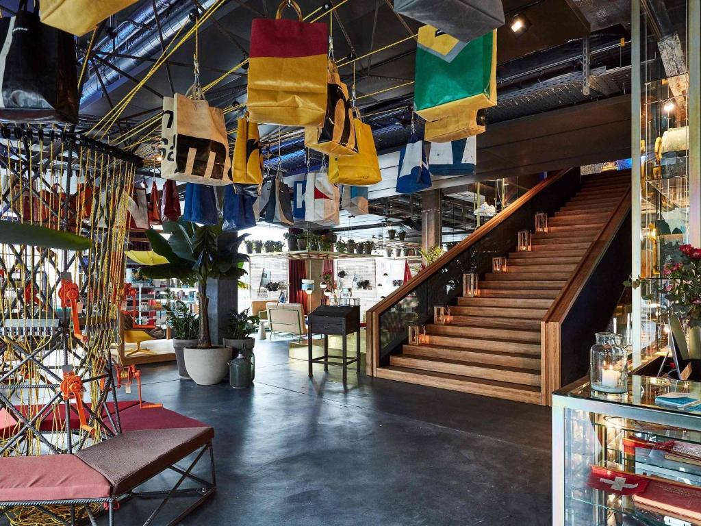 a store with a staircase and colorful bags hanging from the ceilings at 25hours Hotel Langstrasse in Zurich