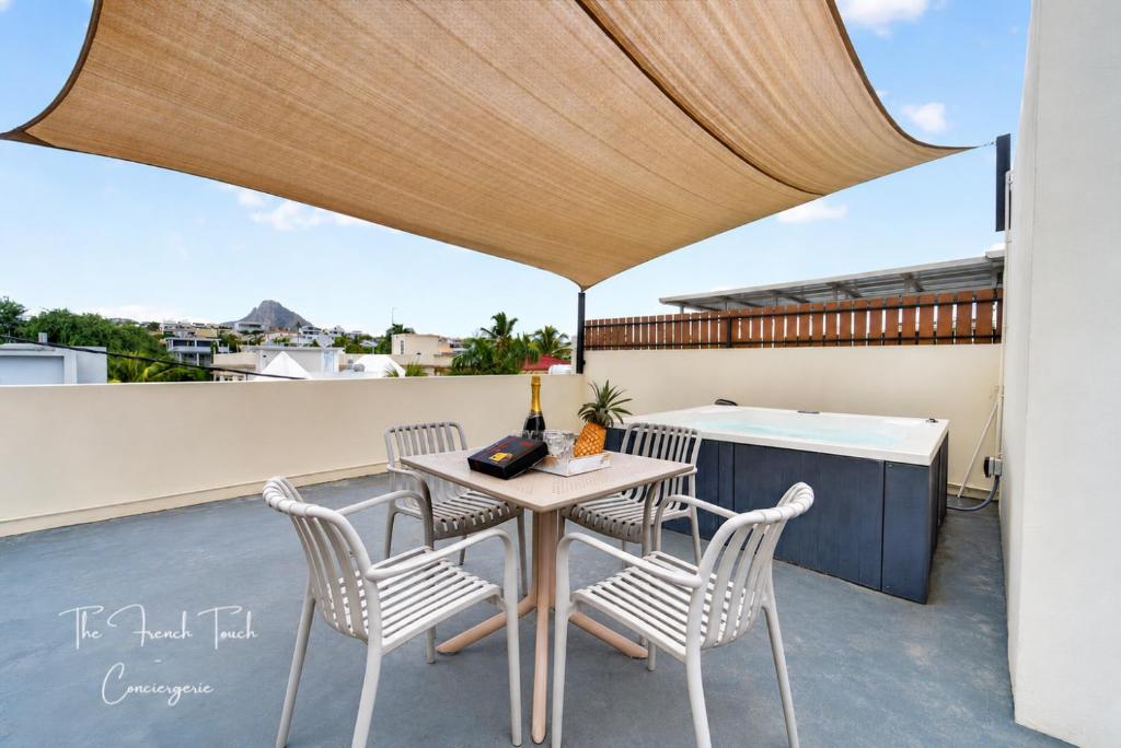 a patio with a table and chairs on a roof at The Jacuzzi Escape in Flic-en-Flac