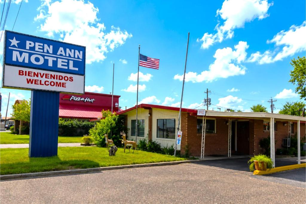 a motel sign in front of a building with an american flag at Pen Ann by Capital O Pharr-McAllen TX in Pharr