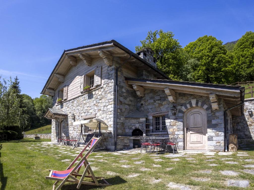 an old stone house with chairs in front of it at Chalet Chalet Anna by Interhome in Grosotto