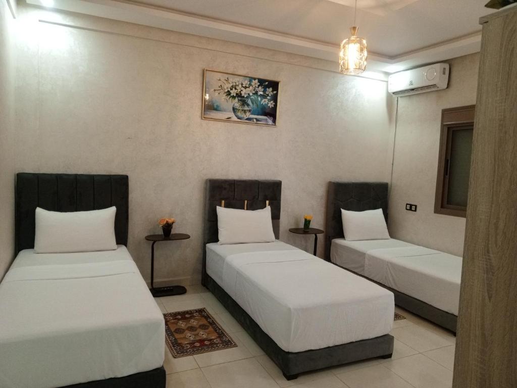 two beds in a room with white sheets at Riad Bollywood Spacious 5 Beds Stay in Benguerir
