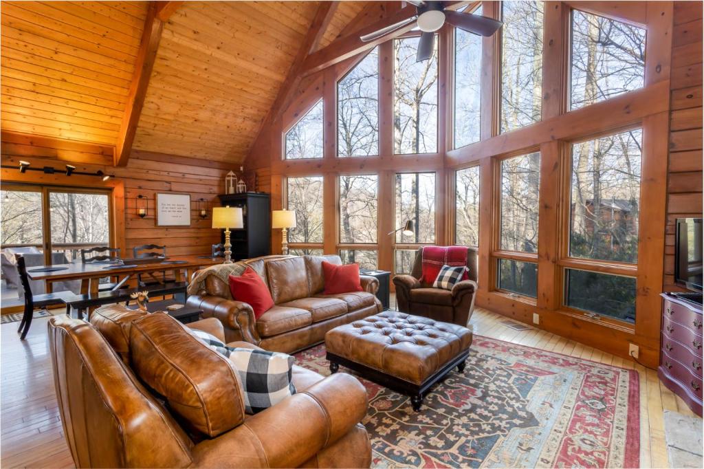 a living room with leather furniture and large windows at Stoney Brook Cabin in Boone