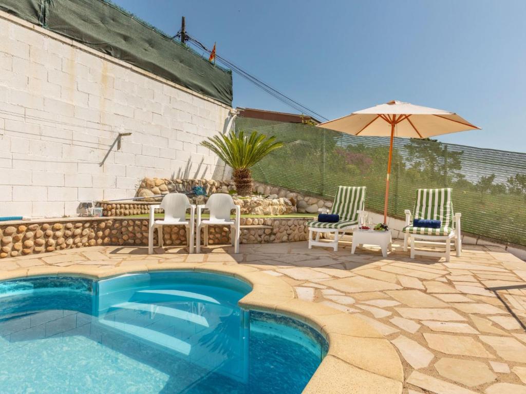 a swimming pool with chairs and an umbrella at Holiday Home Figaro by Interhome in Blanes