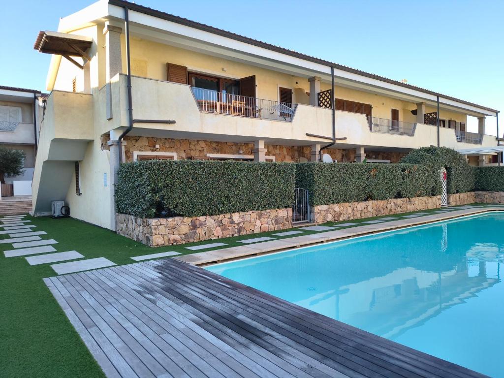 a house with a swimming pool in front of a building at The pool house - Il Gabbiano in Palau