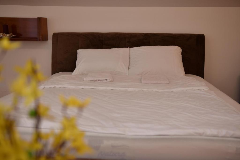 a bed with white sheets and pillows and flowers on it at SIBE Apartments in Banja Luka