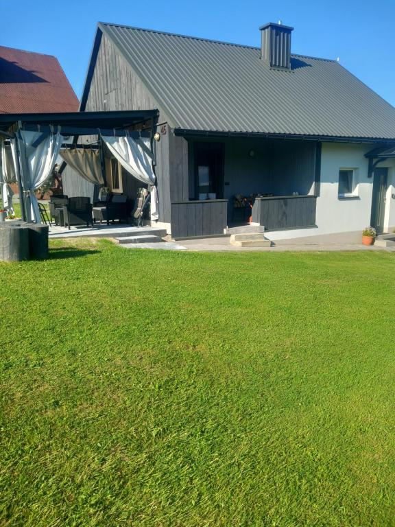 a house with a grass yard and a building at Domek Pod Prehybą -Agroturystyka in Gaboń