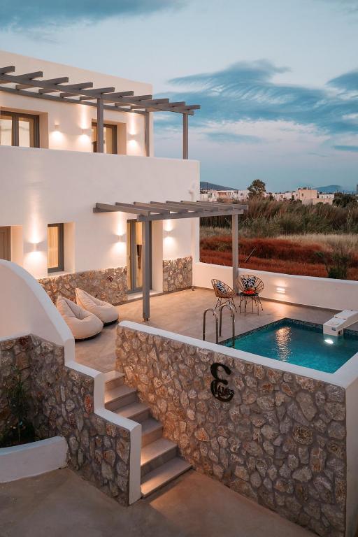 a villa with a swimming pool and a stone wall at Blue Cyclades Villas in Kastraki