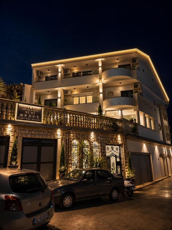a building with two cars parked in front of it at Apartments Nuhi in Ulcinj