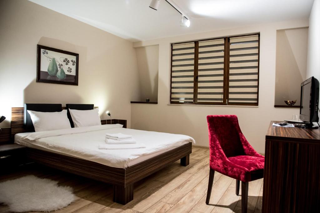 ein Schlafzimmer mit einem Bett und einem roten Stuhl in der Unterkunft Luxe Stay in Târgu Mureș