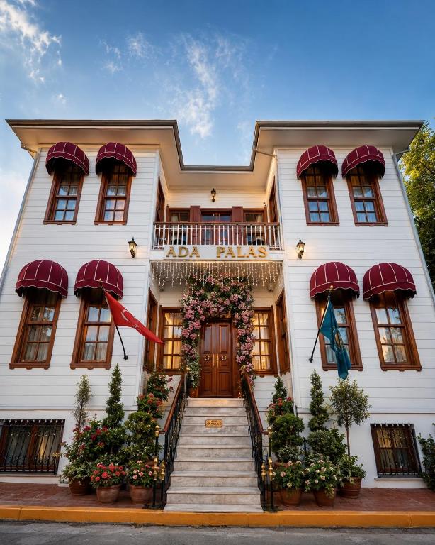 a white house with a staircase leading to the front door at Ada Palas Buyukada in Buyukada