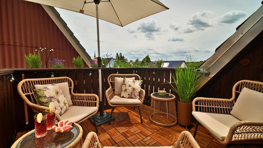 a patio with wicker chairs and a table and an umbrella at Green Loft Schwarzwald - Dach-Balkon--Musik-Ecke in Winzeln