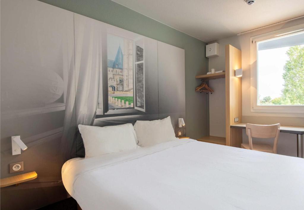 a bedroom with a large white bed and a window at B&B HOTEL Beauvais in Beauvais