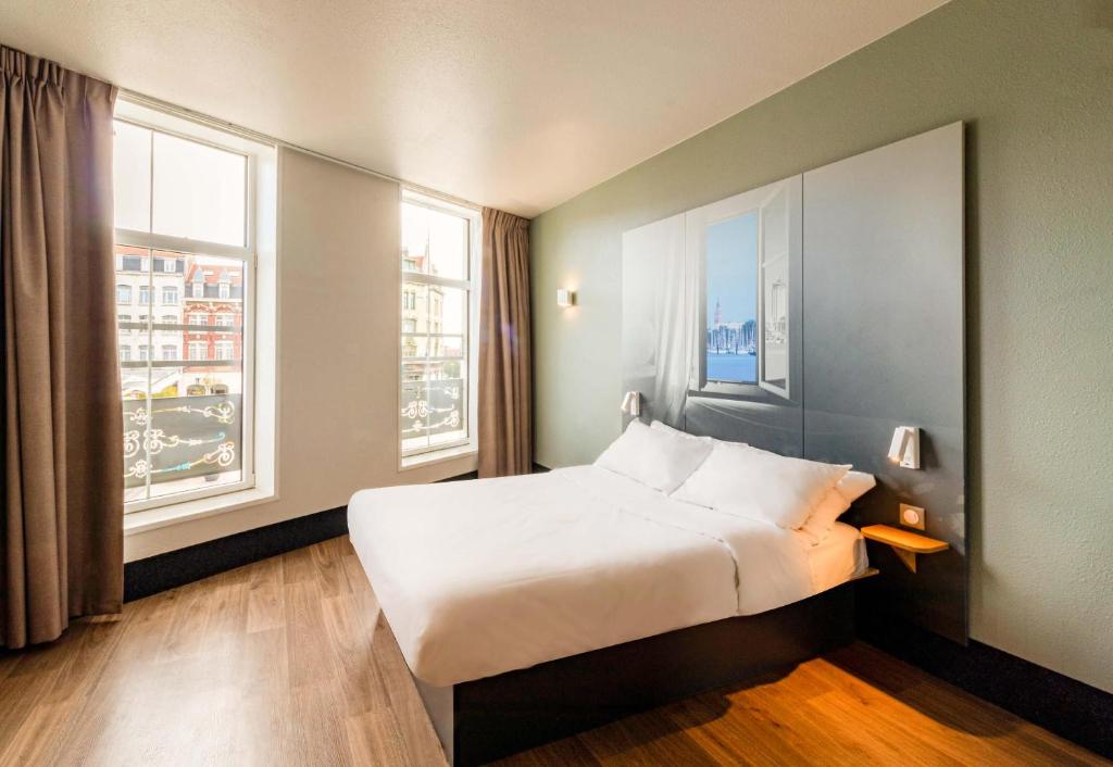 a hotel room with a bed and two windows at B&B HOTEL Dunkerque Centre Gare in Dunkerque