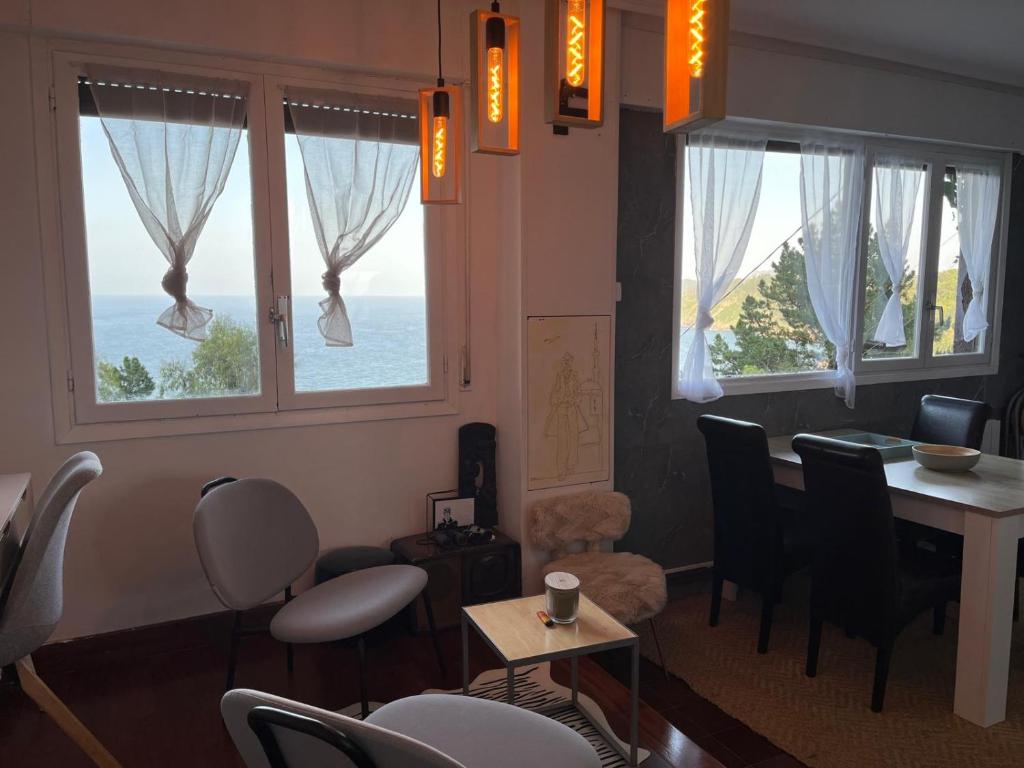 a living room with a table and chairs and windows at Ibinaga Seaview - Auto checking property in Ibarrangelu