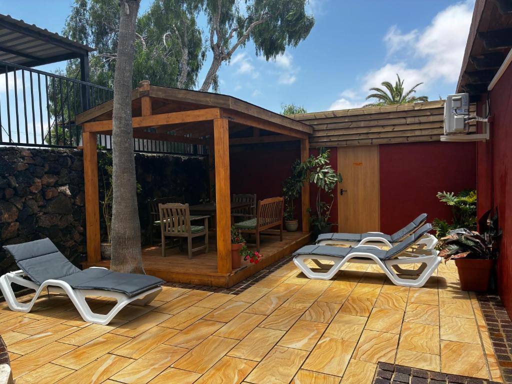 a patio with lounge chairs and a gazebo at Villa Lajares Red House Fuerteventura in Lajares