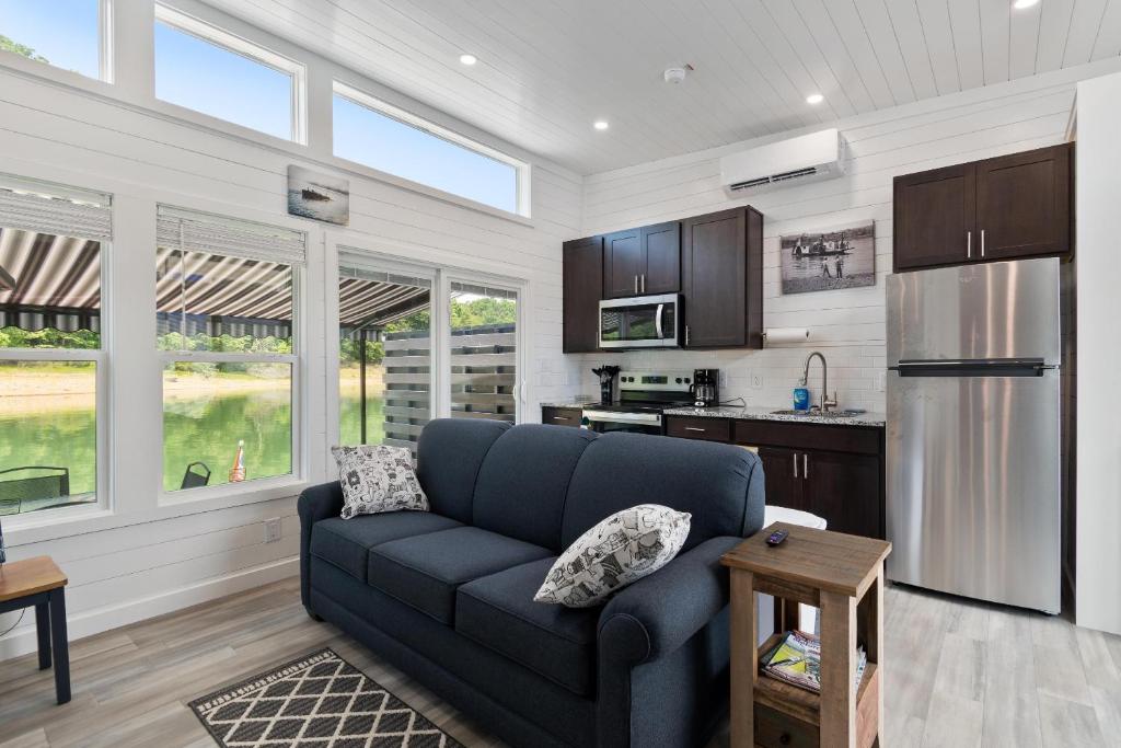 a living room with a blue couch and a kitchen at Miss Madison - Pet Friendly Floating House in Russell Springs