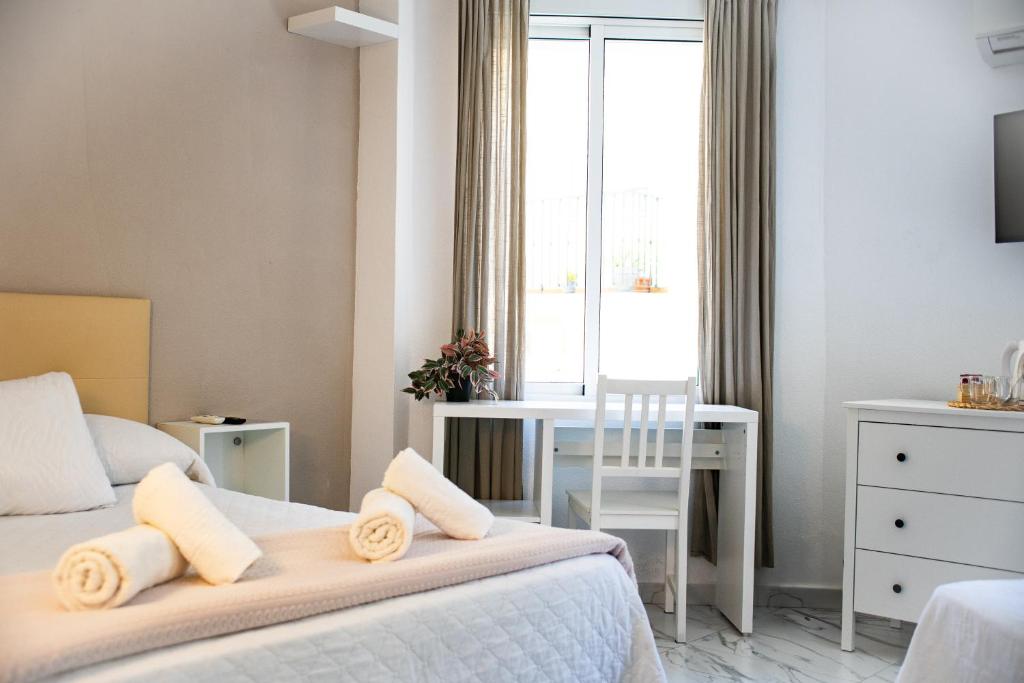 a bedroom with two beds and a desk and a window at Hotel Avenida in Vélez-Málaga