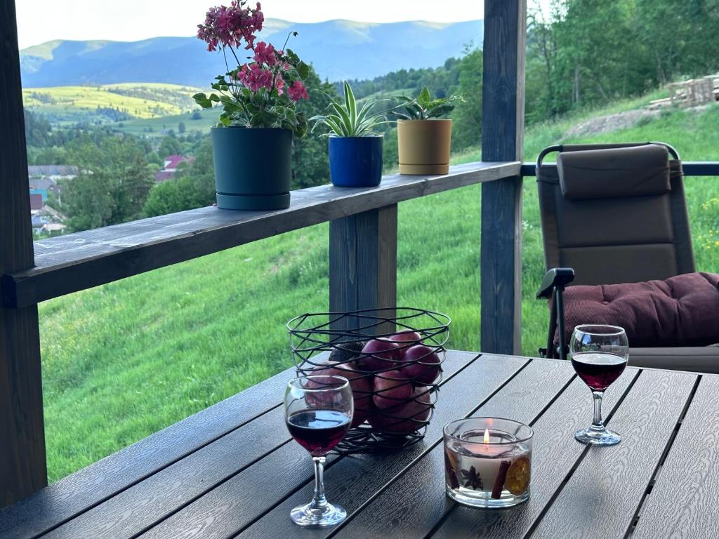 two glasses of wine on a wooden table with a view at Borzhava View Chalet in Nizhniy Studenyy