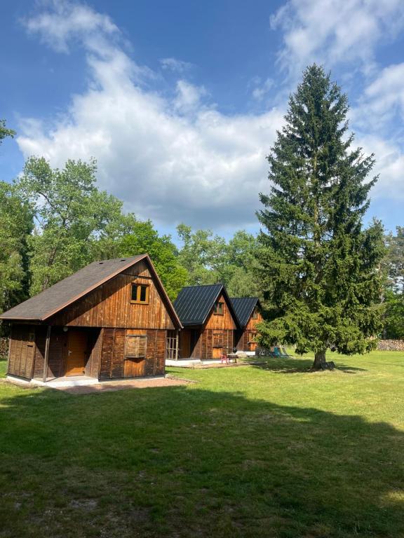 two wooden barns in a field with a tree at Koliba Hoděšovice in Býšť