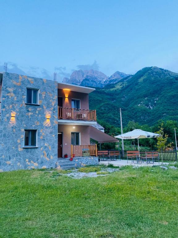 a large stone house with a balcony and tables at Guesthouse Natyra Theth in Theth