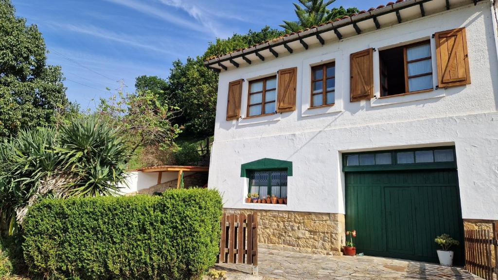 a white house with a green garage at La casina de Pili in Villaviciosa