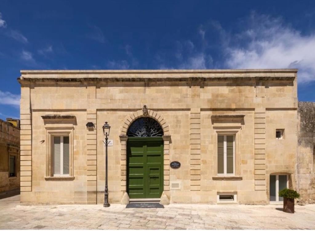 a large stone building with a green door at Casa Novecentoundici in Castrignano deʼ Greci
