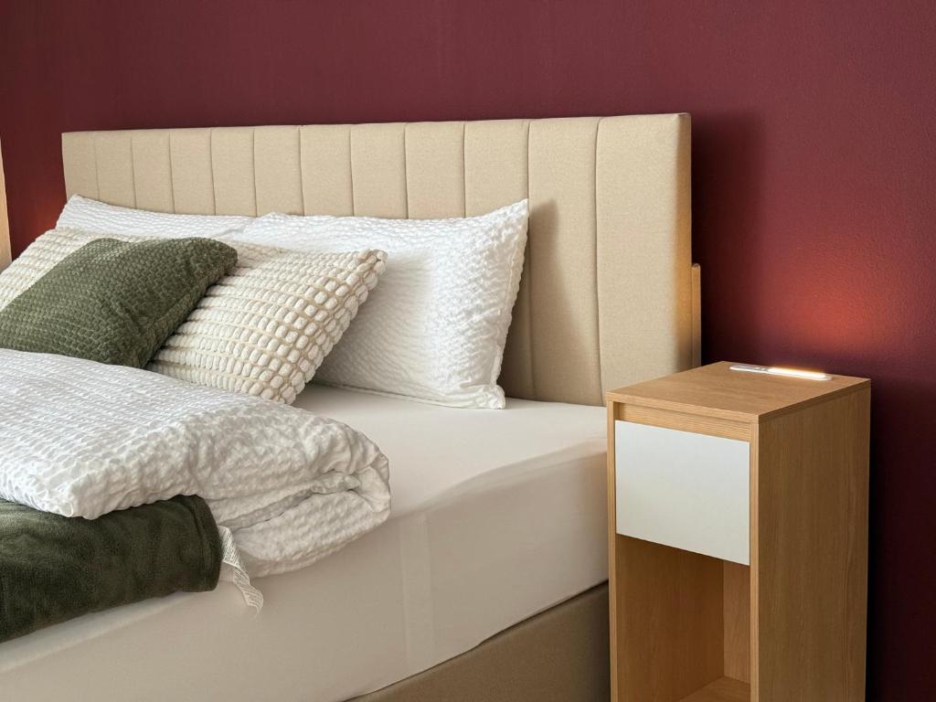 a bed with white pillows and a wooden night stand at Ferienwohnung Eulenwinkel in Pappenheim