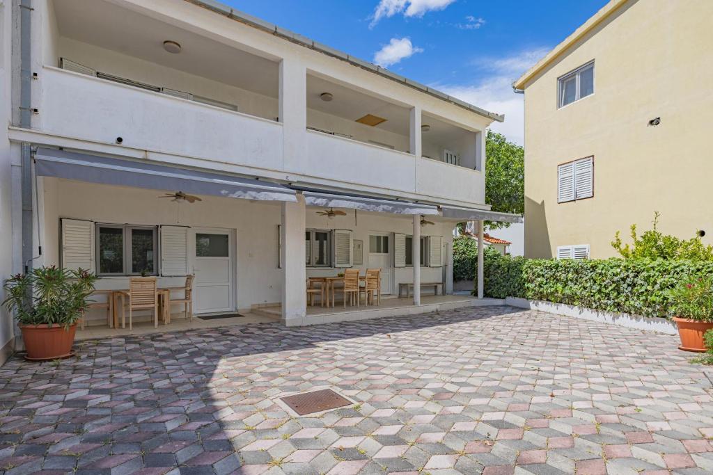 a large house with a patio with a table and chairs at Apartments at Frapa in Rogoznica