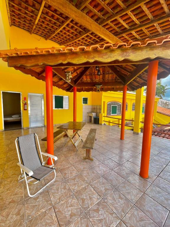 a room with a chair and a table and yellow walls at Pousada ENCANTOS de PERUÍBE in Peruíbe