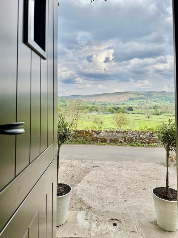 a door with a view of a field through a window at Luxury cottage for 2 in Castleton - Peak District retreat - Panoramic Views & Log burner in Castleton