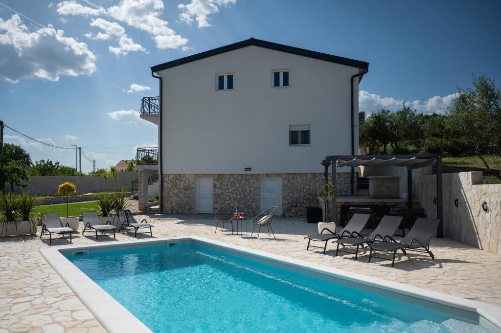a villa with a swimming pool in front of a house at Villa The Rock in Unešić
