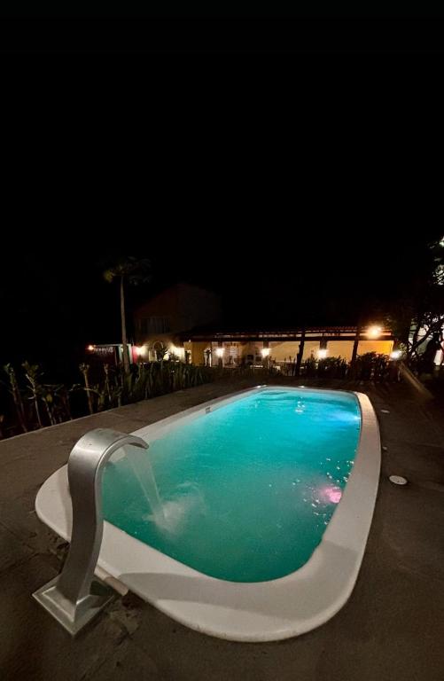 a swimming pool at night with a white bench around it at Pousada Padre Pio CE in São Benedito