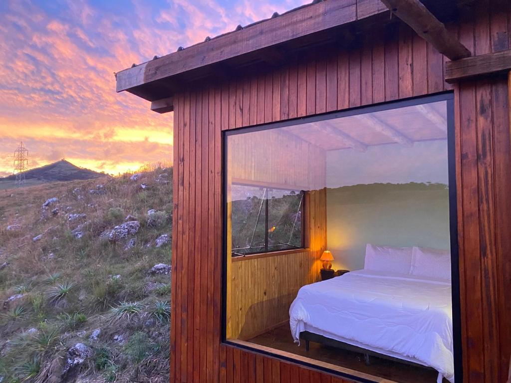 a bedroom with a large window in a cabin at Cloud Valley in Bom Jardim da Serra