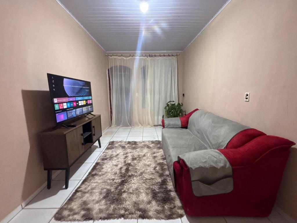 a living room with a couch and a flat screen tv at Refúgio da Sombra House in Rondonópolis