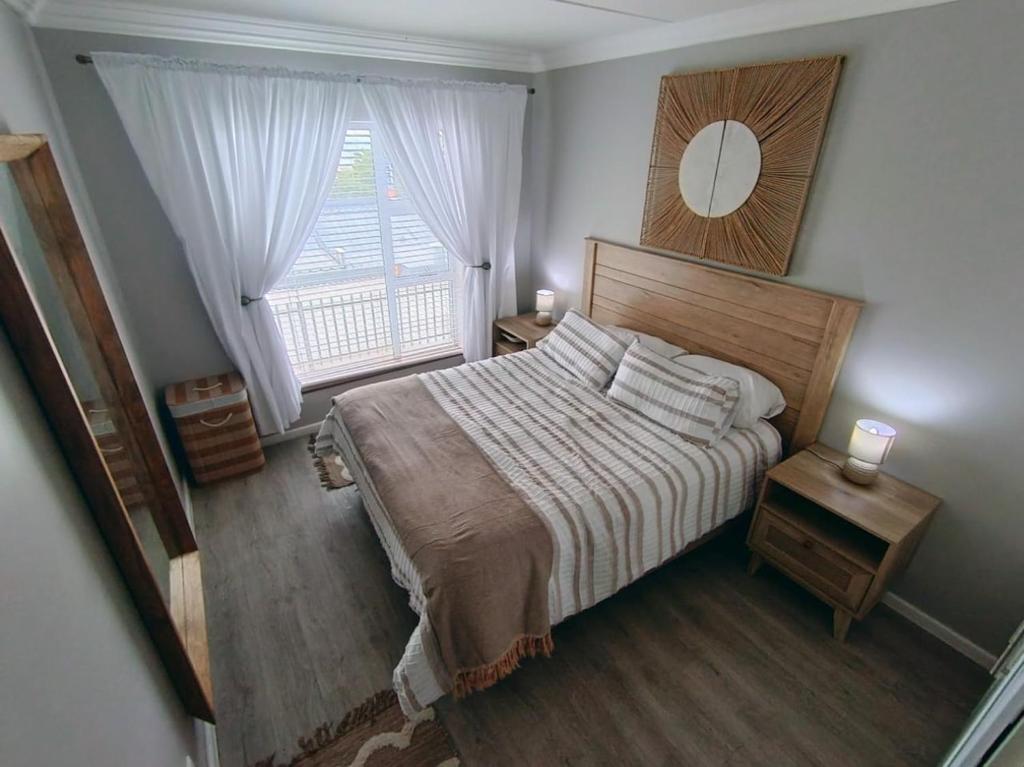 a bedroom with a bed and a large window at 6 Vasco Mews in Mossel Bay