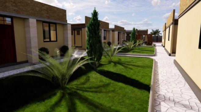 a green yard with houses and plants in a courtyard at Karatu Boutique Lodge in Karatu