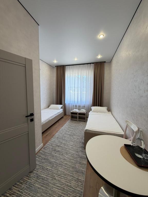 a hotel room with two beds and a table at Comfort Altyn-Emel in Kalīnīno
