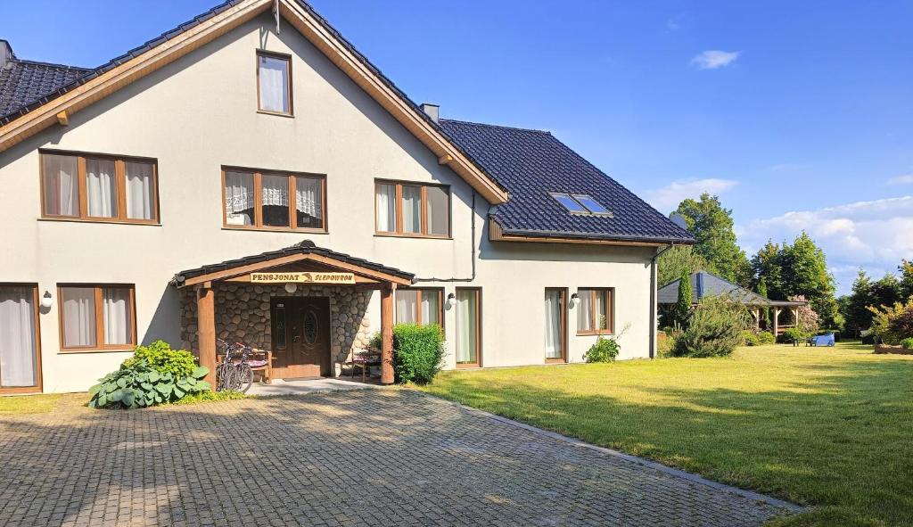 a large white house with a driveway at Pensjonat Ślepowron in Międzywodzie