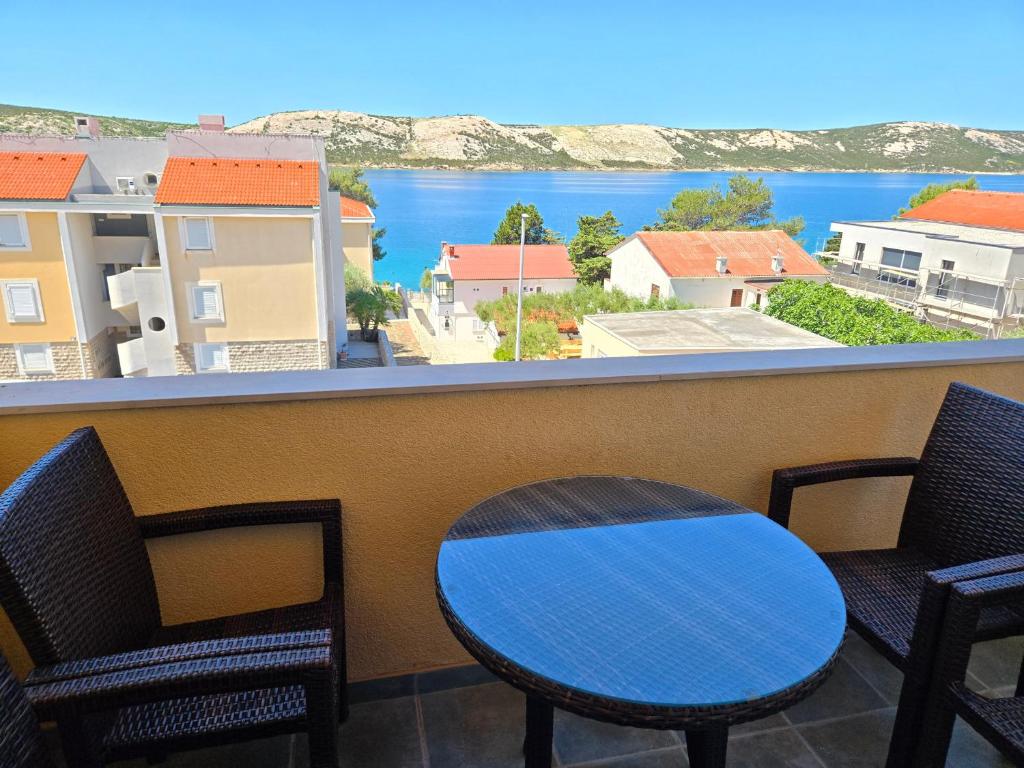 a table and chairs on a balcony with a view of the water at Apartmani Kovač in Stara Novalja