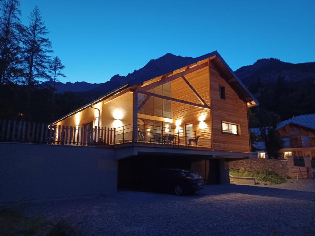 a house with a wrap around deck at night at le chalet de st Anne in Jausiers