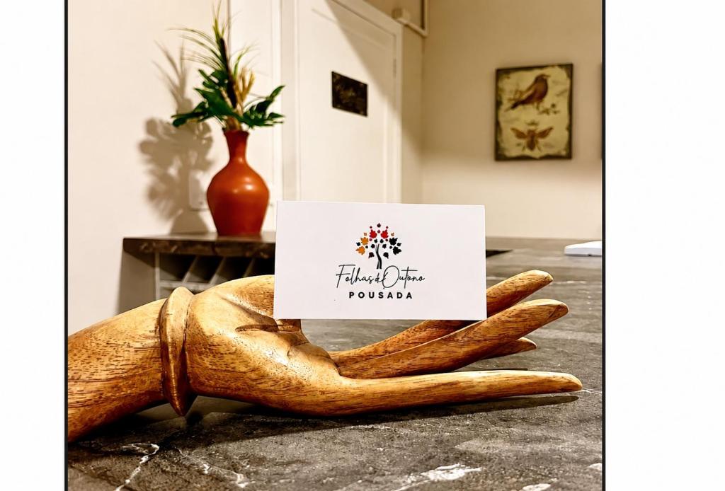 a hand holding a sign on top of a counter at Pousada Folhas de Outono in Canela