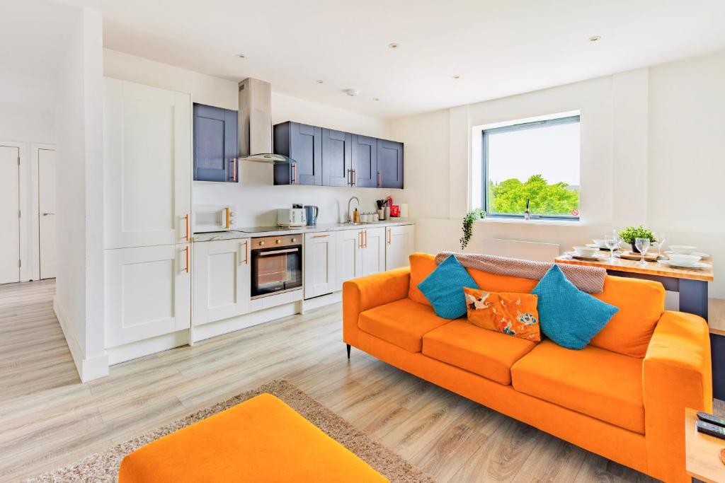 a living room with an orange couch and a kitchen at Stylish Central Location Apartment in Norwich