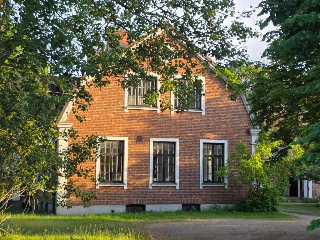 an old red brick house with white windows at Artist eremitage Leonora - Historic schoolhouse apartment in Fjälkinge