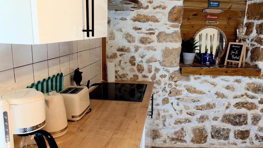 a kitchen with a stone wall and a counter at Maison rénovée, centre médiéval de Belvès in Belvès