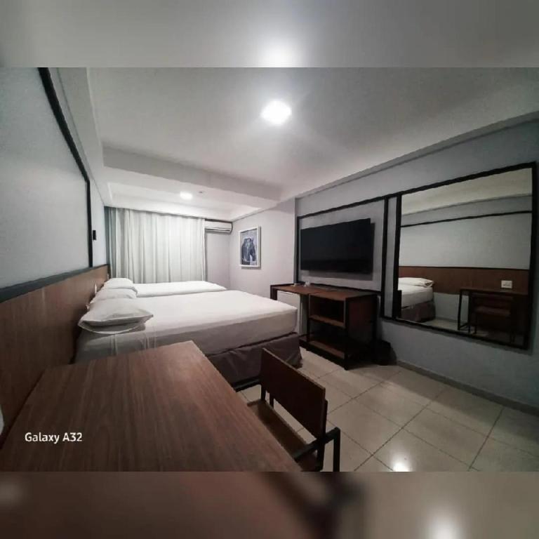 a bedroom with a bed and a table and a television at Pratti Hotel in Linhares